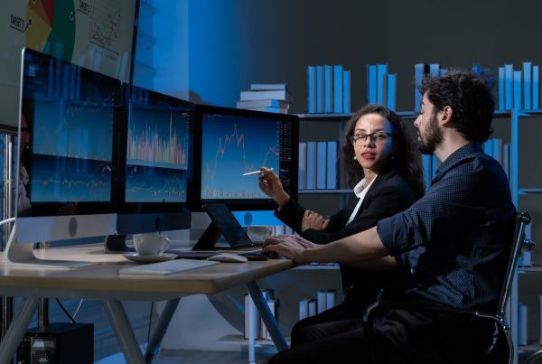Two people analysing AI data on desktops